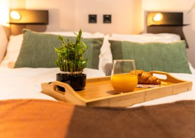 Close-up of bed with breakfast tray, juice and croissant – inviting stay at Astoria Loft Apartment Budapest