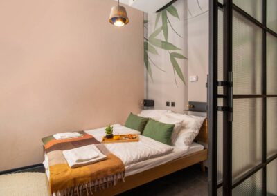 Cozy bedroom with minimalist decor, bamboo-themed wall design, and sliding glass door – Astoria Loft Apartment in Budapest