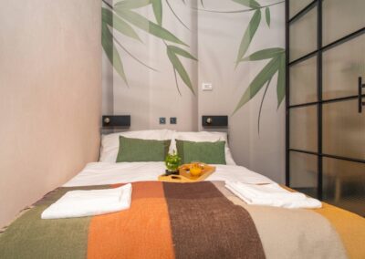 Front view of double bed with soft linens, bamboo wall art, and breakfast tray – central Budapest holiday apartment