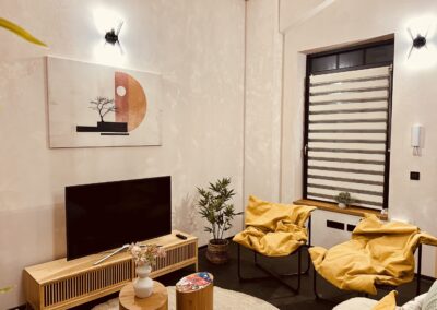 Living room with TV, modern artwork, yellow armchairs, and large window – vacation rental in Budapest